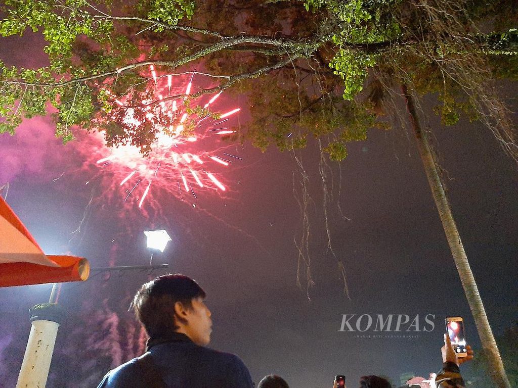 Pendar sinar dari kembang api nampak di langit diantara pepohonnan di Alun-alun Magelang, Kota Magelang, Minggu (1/5/2022).