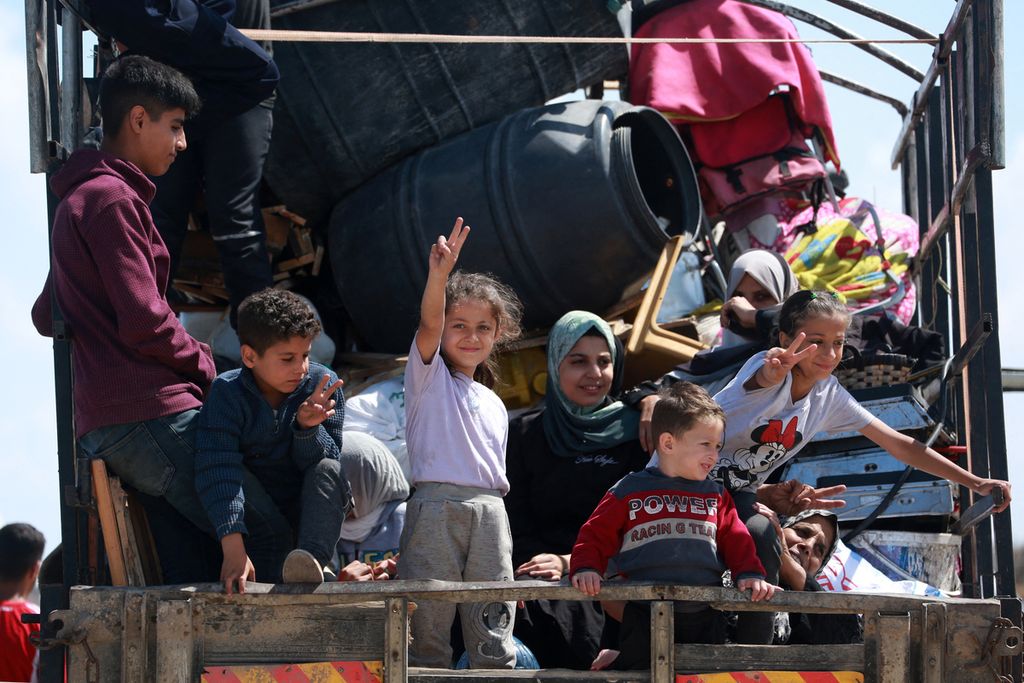 Two children raise their fingers to form the letter V which means <i>victory</i> or victory on the back of a truck that is taking them to a location near Deir el-Balah, Gaza City, May 7 2024.