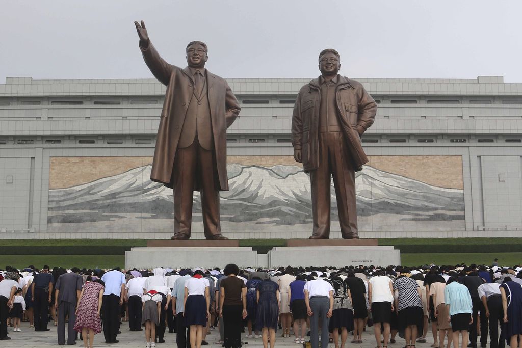 Warga Korea Utara membungkuk memberi hormat pada patung mendiang pemimpin mereka, Kim Il Sung (kiri) dan Kim Jong Il, di Mansu Hill, Pyongyang, Korut, Sabtu (8/7/2023).
