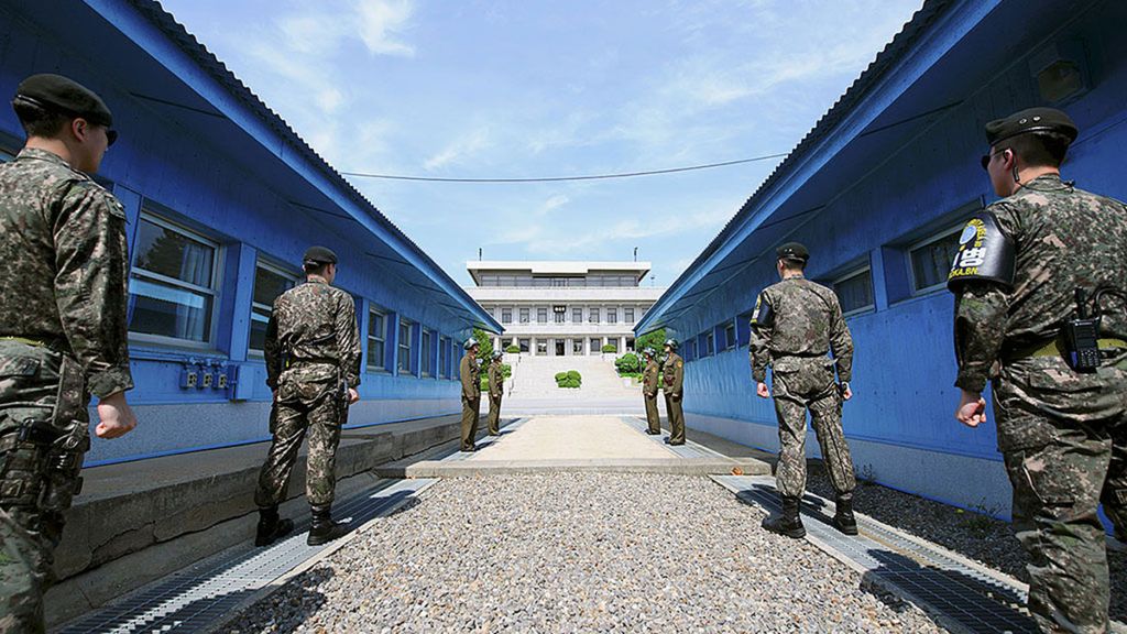 Tentara Korea Selatan (depan) dan tentara Korea Utara (belakang) berjaga-jaga di depan garis demarkasi di masing-masing sisi yang berada di Desa Panmunjom, Zona Demiliterisasi. Hari ini, Jumat (27/4/2018), Presiden Korsel Moon Jae-in dan Pemimpin Korut Kim Jong Un menggelar pertemuan tingkat tinggi.