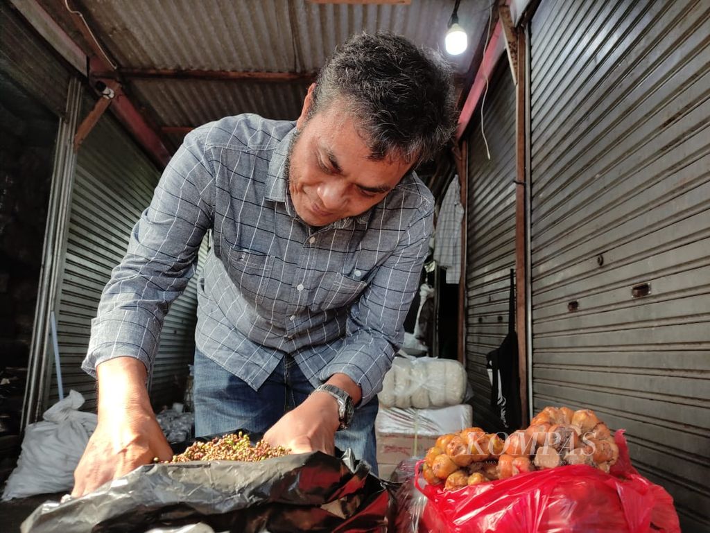 Cosmos Silalahi mengecek bumbu-bumbu yang dijualnya di Pasar Senen, Jakarta, Jumat (29/9/2023).