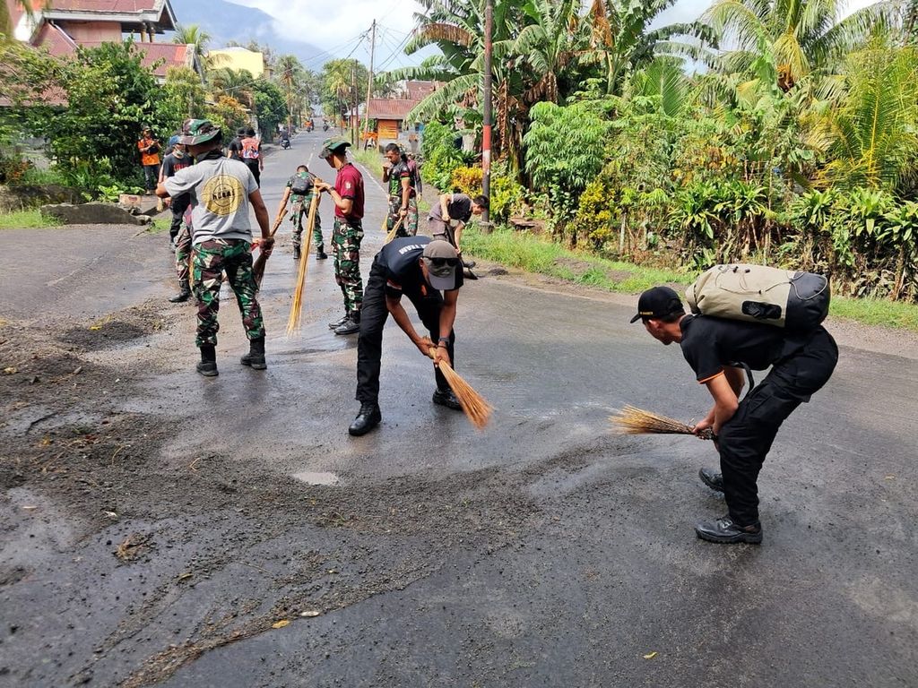 Tim SAR dan warga membersihkan jalan desa yang tertutup abu vulkanik Gunung Ruang, Senin (22/4/2024). Saat ini, status gunung api di Kabupaten Kepulauan Sitaro, Sulawesi Utara, itu diturunkan dari Awas menjadi Siaga.