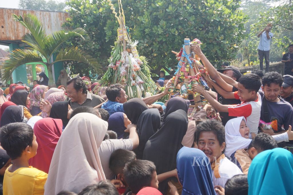 Warga berebut sayur-mayur dan jajanan yang dipasang di gunungan dalam perayaan Tahun Baru Islam 1444 H di Sokaraja Kulon, Sokaraja, Banyumas, Jawa Tengah, Sabtu (30/7/2022).
