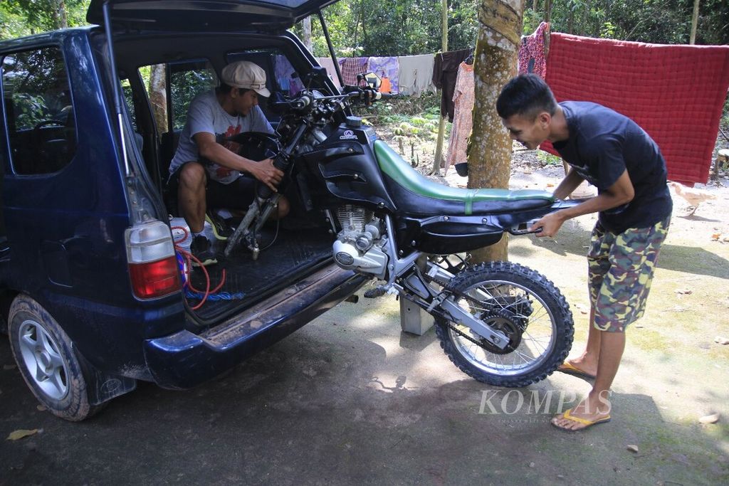 Petugas Bagian Rumah Tangga <i>Kompas</i> Palembang, Rudi Yanto, menurunkan sepeda motor trail untuk menyusuri jalan rusak sepanjang Sepucuk hingga Cengal di Kabupaten Ogan Komering Ilir, Sumatera Selatan, Selasa (25/4/2017).