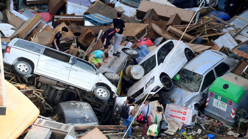 Orang-orang memanjat mobil yang menumpuk setelah banjir di Sedavi, selatan Valencia, Spanyol, Rabu (30/10/2024). 