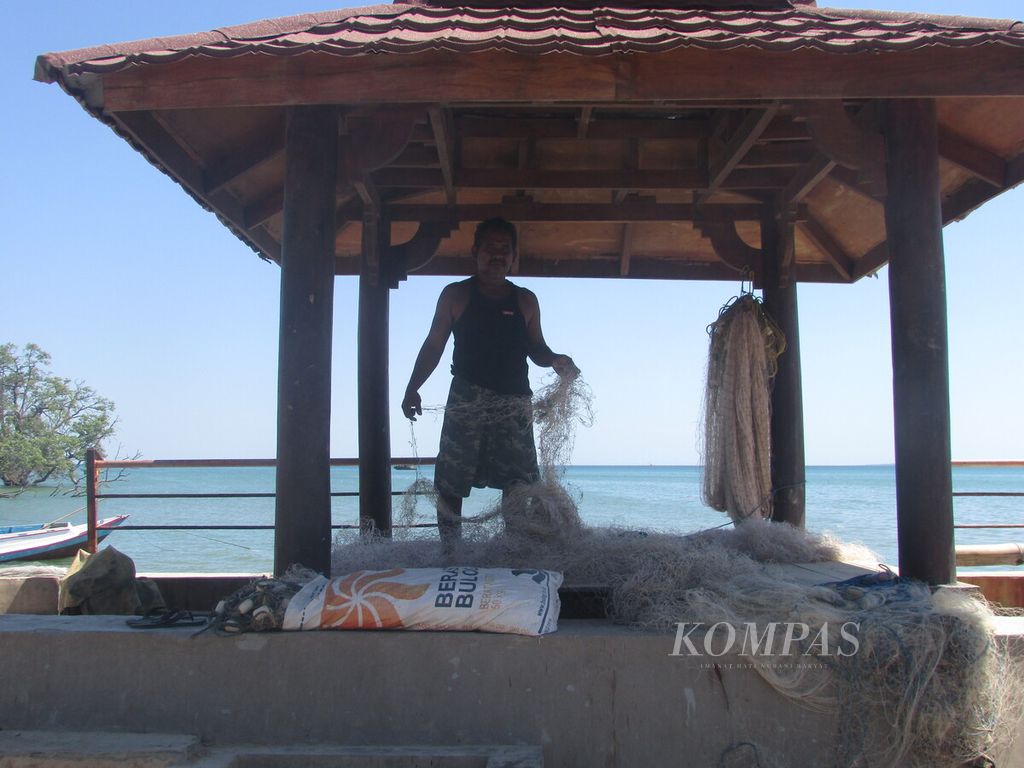 Abdul Syukur (52), nelayan Oesapa Kupang, NTT, sedang mengurai tali nilon dari pukat jaring yang rusak, 26 April 2021. 