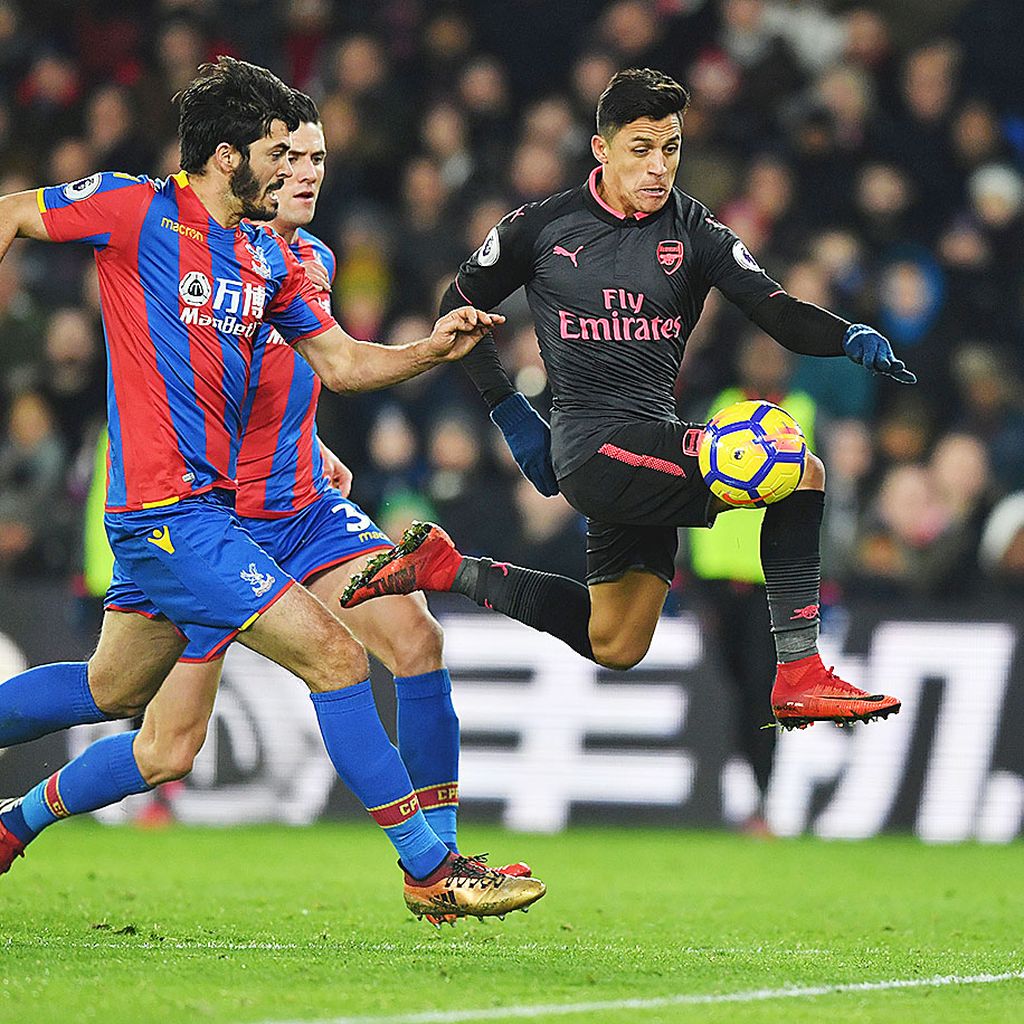 Alexis Sanchez mengontrol bola dalam tekanan  pemain Crystal Palace sebelum menceploskan gol ketiga  Arsenal pada Laga Liga Inggris di Stadion Selhurts Park, London, Jumat (29/12) dini hari WIB. Arsenal menang 3-2 dan menjaga peluang masuk empat besar klasemen.