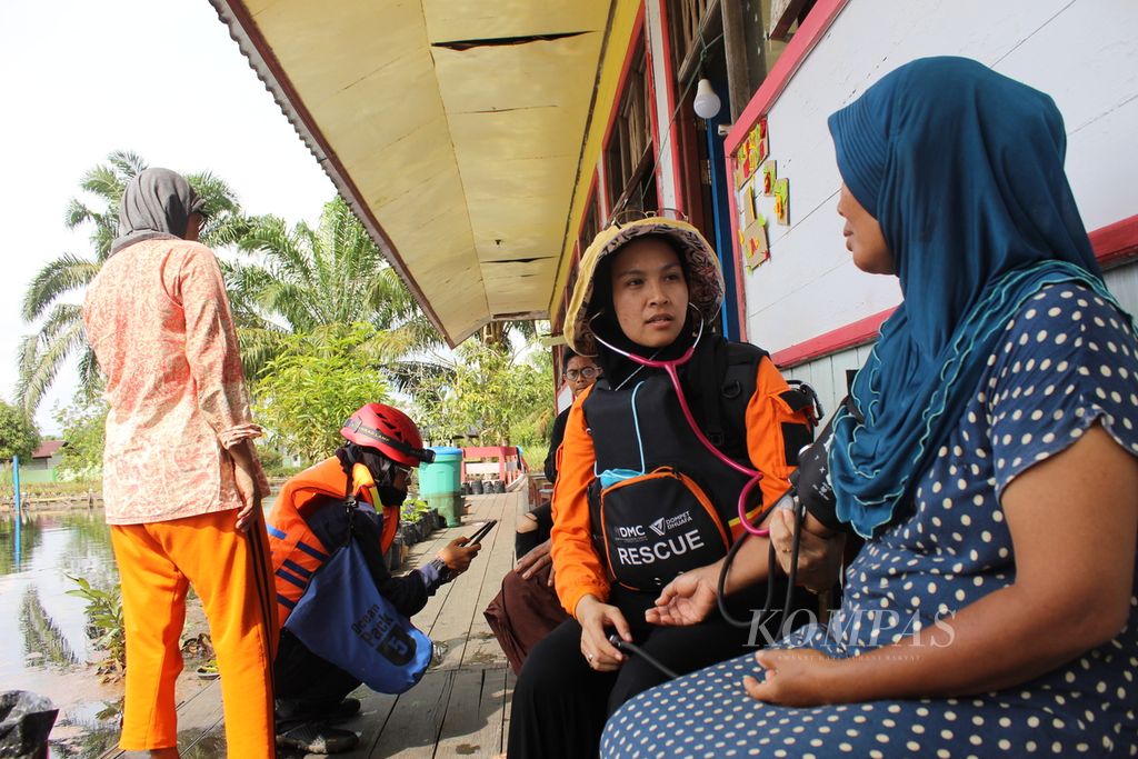 Petugas kesehatan dan sejumlah sukarelawan bencana banjir memeriksa kesehatan pengungsi di SDN II Tanjung Terantang, Kabupaten Kotawaringin Barat, Kalteng, Senin (31/10/2022).