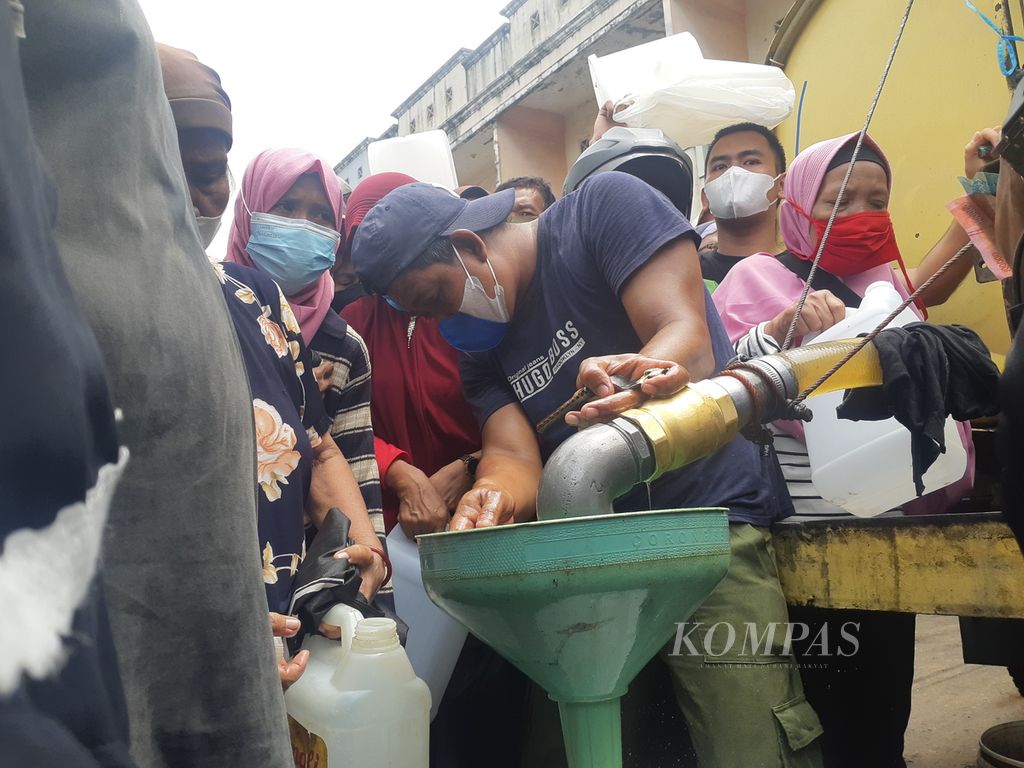 Seorang petugas sedang menuangkan minyak curah ke dalam jerigen milik warga yang mengantre minyak goreng di Pasar Alang-Alang Lebar, Palembang, Sumatera Selatan, Sabtu (5/3/2022). Ratusan orang mengatre untuk mendapatkan minyak yang sampai saat ini sulit didapat.