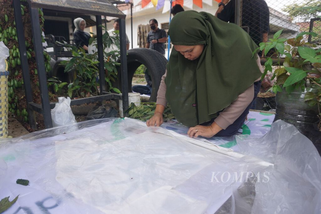 Juariah menggulung kaus <i>ecoprint</i> di Bank Sampah Srayan Makarya, Purwokerto, Banyumas, Jawa Tengah, Minggu (27/8/2023).