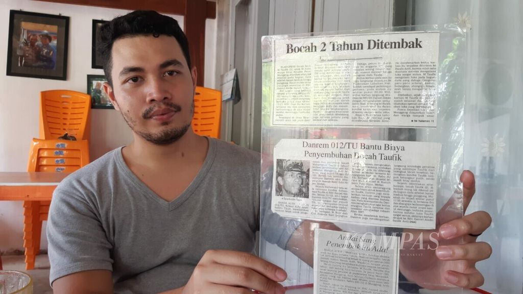 Taufik (23), warga Aceh Barat Daya, Aceh, Minggu (15/8/2021), memperlihatkan kliping koran yang memberitakan dirinya tertembak saat berusia dua tahun. Korban konflik Aceh berharap penyelesaian reparasi segera dilakukan.