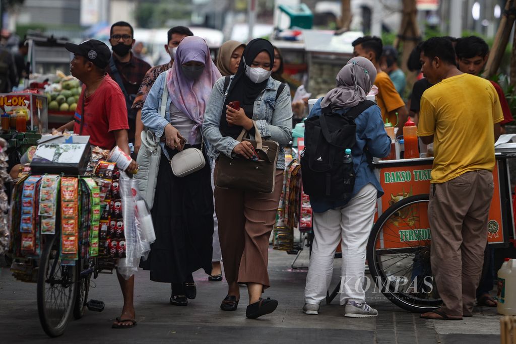 Warga berjalan di antara pedagang kaki lima di Jalan Blora, Jakarta, Jumat (8/12/2023). 