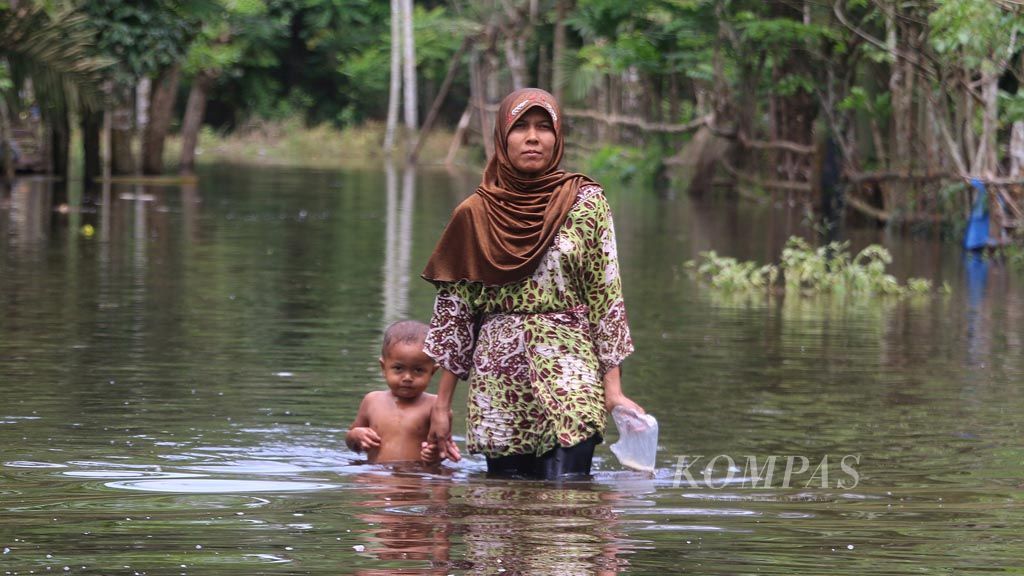 Warga menerobos banjir di Desa Cot U Sibak, Kecamatan Lhoksukon, Kabupaten Aceh Utara, Provinsi Aceh, Kamis (7/12). Hujan deras dan rusaknya tanggul penahan di beberapa sungai menyebabkan  23 kecamatan di Aceh Utara dilanda banjir sejak enam hari terakhir. Sebanyak 15.000 warga  mengungsi karena rumah mereka tergenang.