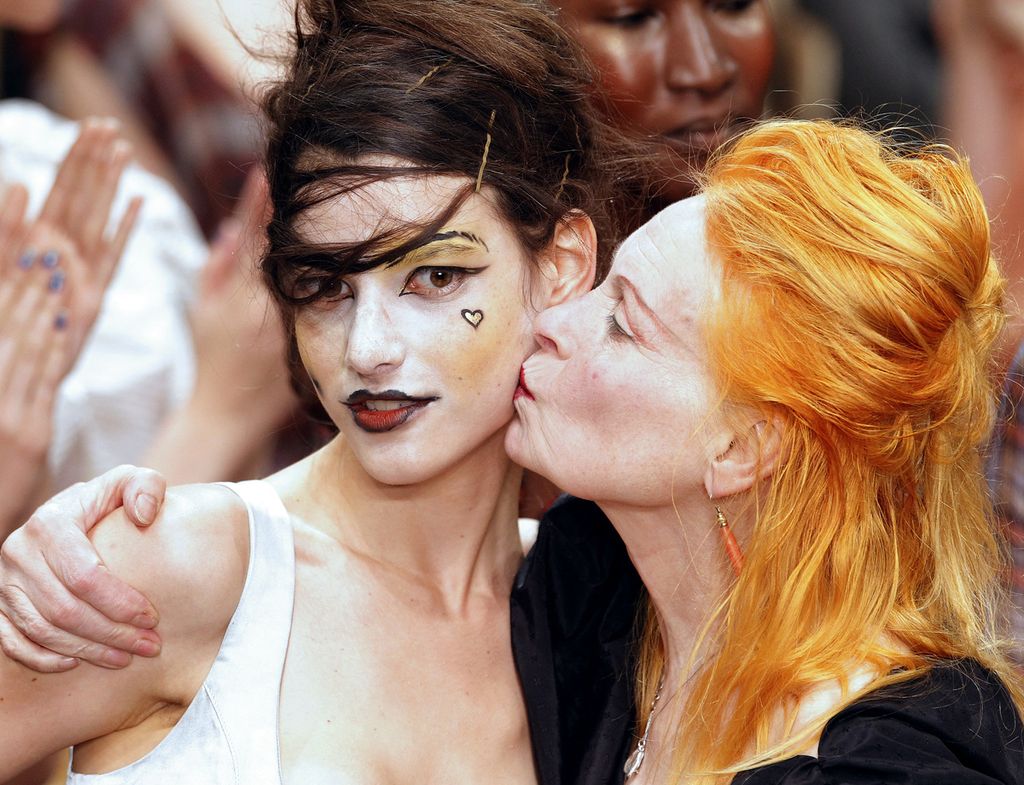 Desainer Inggris, Vivienne Westwood (kanan), mencium pipi seorang model yang mempersembahkan kreasinya pada pameran koleksi siap pakai musim semi/musim panas 2011 di Paris, Perancis, pada 1 Oktober 2010. Westwood meninggal di London pada 29 Desember 2022 dalam usia 81 tahun.