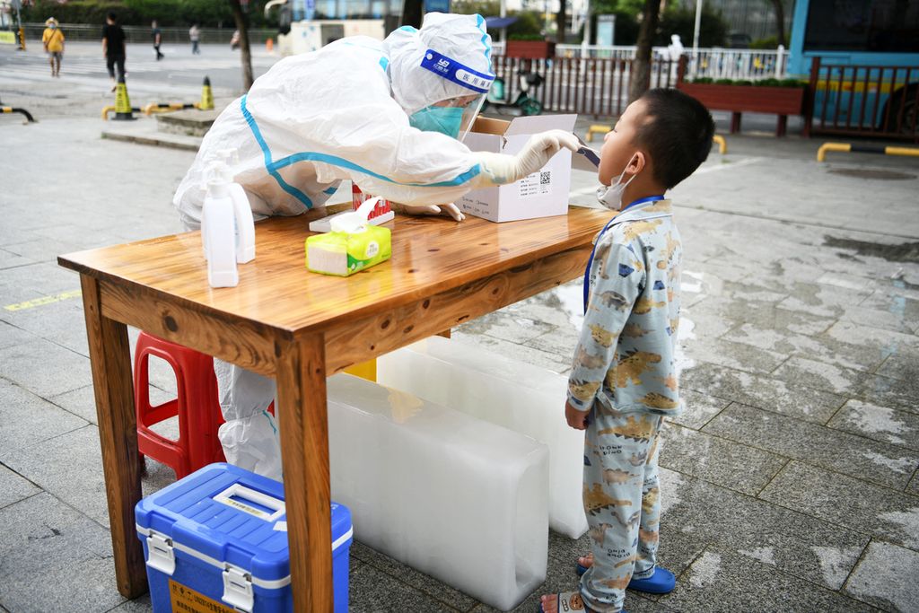 Pekerja kesehatan mengambil sampel usap dari anak kecil, di Nanchang, China, Kamis (21/7/2022). 