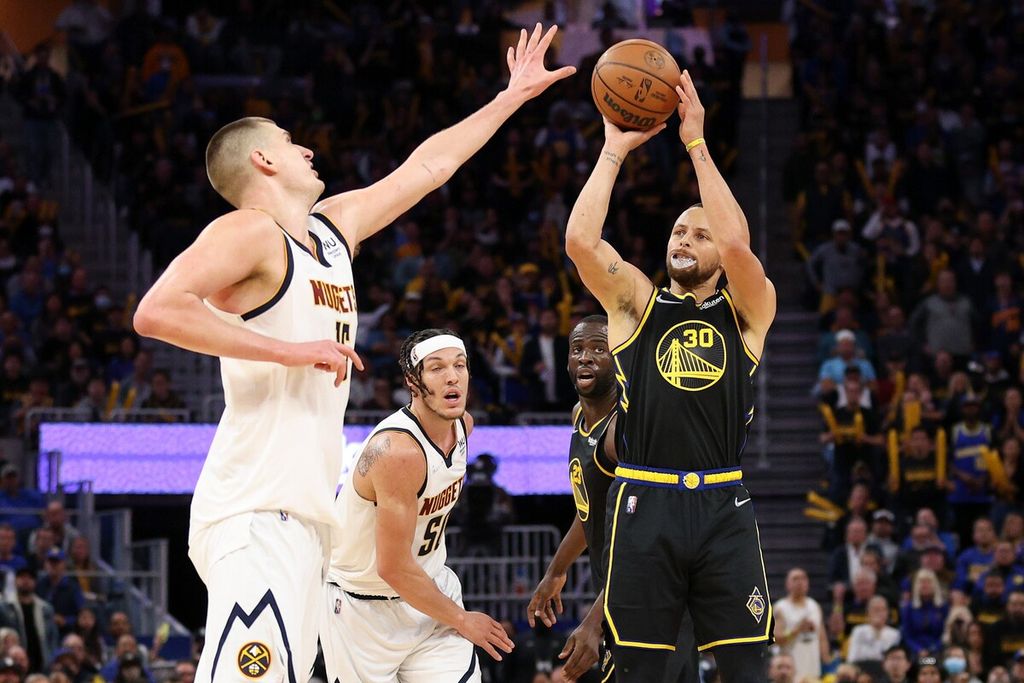 <i>Guard </i>Golden State Warriors Stephen Curry (kanan) melempar bol dengan pengawalan bintang Denver Nuggets Nikola Jokic laga kelima babak pertama <i>playoff </i>NBA antara Golden State Warriors dan Denver Nuggets di Chase Center, San Francisco, Kamis (28/4/2022) siang WIB. 