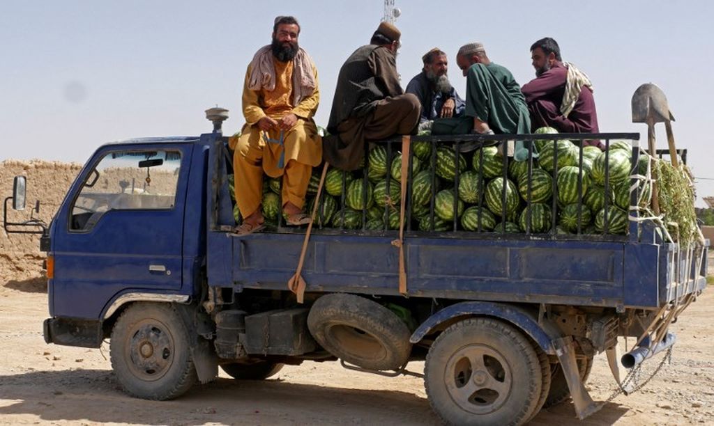 Para pekerja duduk di atas truk yang mengangkut semangka di sebuah pasar buah di Provinsi Farah, Afghanistan, 31 Mei 2022. 