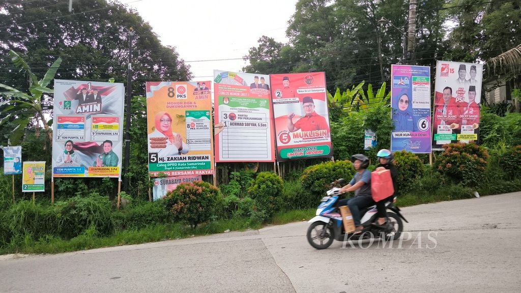 Pengendara sepeda motor melintas di jalan yang penuh dengan baliho calon anggota legislatif di Kecamatan Samarinda Ulu, Kota Samarinda, Kamis (21/12/2023).