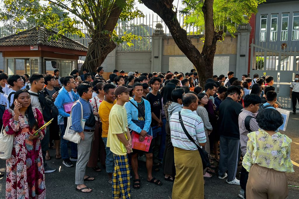 Warga Myanmar mengantre di depan gerbang Kedutaan Besar Thailand di Yangon, 16 Februari 2024, untuk mendapatkan giliran pembuatan visa.  