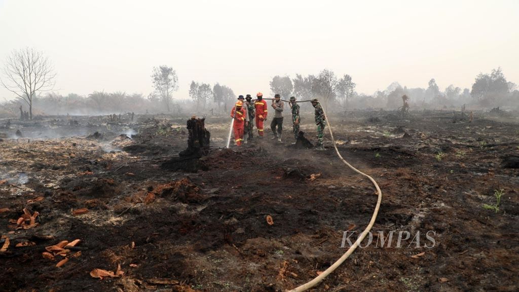 Petugas gabungan membasahi lahan gambut yang masih mengeluarkan asap di Desa Merbau, Kecamatan Bunut, Kabupaten Pelalawan, Provinsi Riau, pertengahan September 2019.