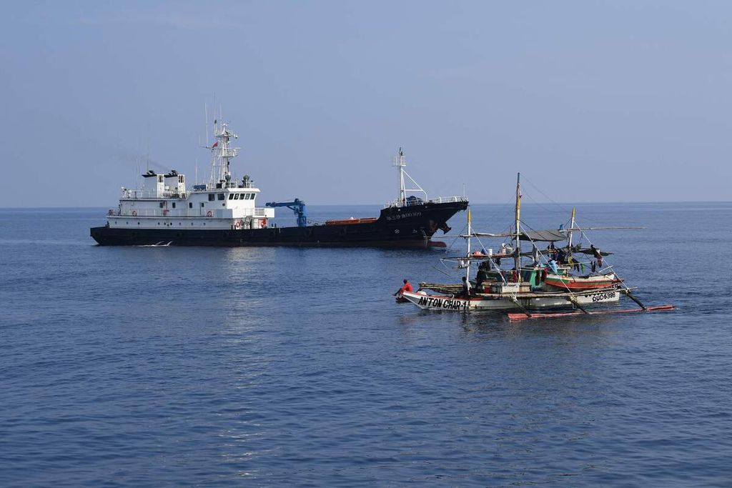 Kapal nelayan Filipina melintas di dekat kapal milisi maritim China di dekat gugusan karang Scarborough yang dikuasai China di Laut China Selatan. Pihak China menguasai Scarborough Shol sejak tahun 2012 dari Filipina dan menempatkan sejumlah kapal untuk membatasi pencarian ikan oleh nelayan Filipina di sana. 