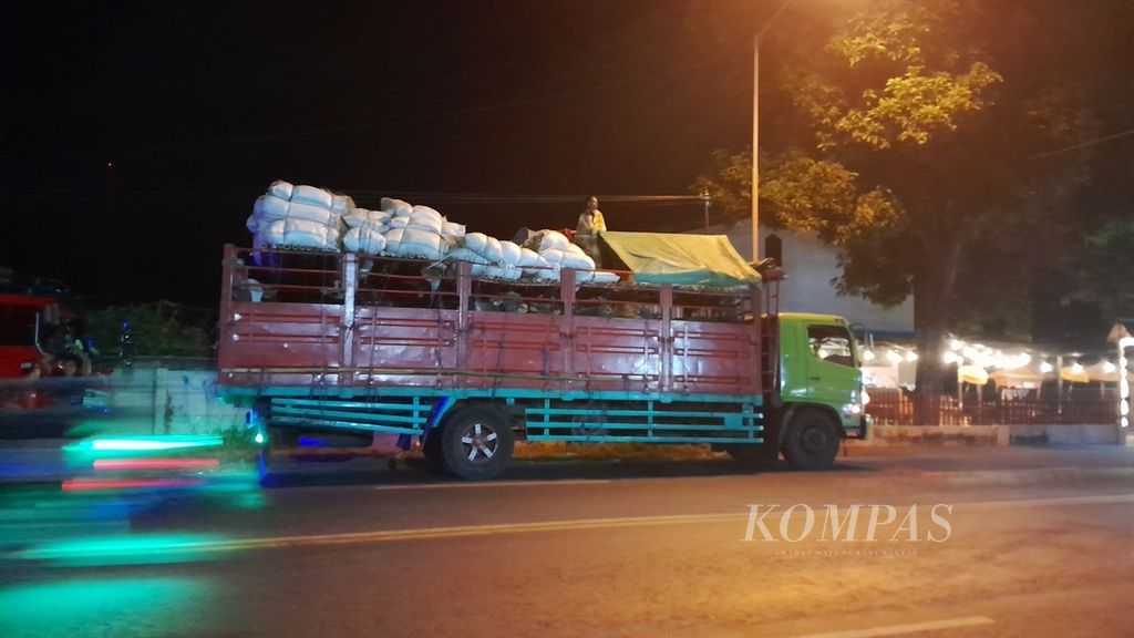 Di depan Kantor Imigrasi Banyuwangi, di Banyuwangi, Jawa Timur, seorang peternak berdiri di atas bak truk bermuatan sapi asal Bima, Nusa Tenggara Barat, yang hendak menuju Jakarta, Selasa (30/5/2023) malam. Selama perjalanan, para peternak menempati tenda kecil di atas truk. Di belakang mereka adalah kantong pakan sapi dan kebutuhan pokok. Bak truk bagian bawah ditempati lebih dari 20 ekor sapi.