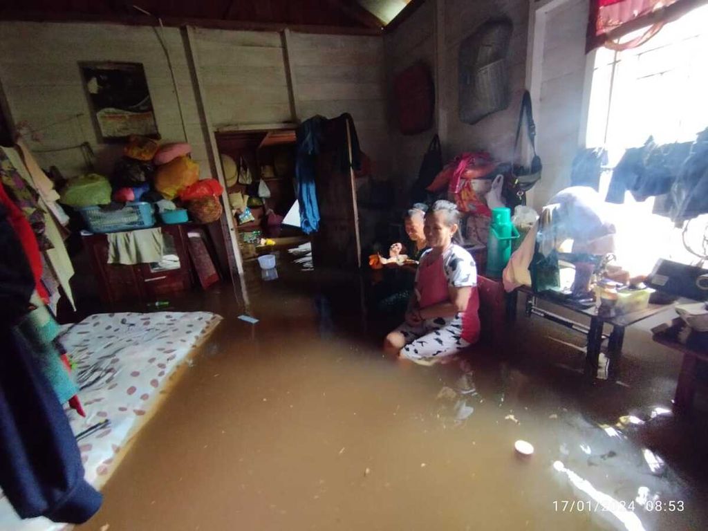Mahmudah (78), warga Kelurahan Briwit, Kecamatan Murung, Kabupaten Murung Raya, menjaga barang-barangnya di rumah yang terendam banjir pada Rabu (17/1/2024).