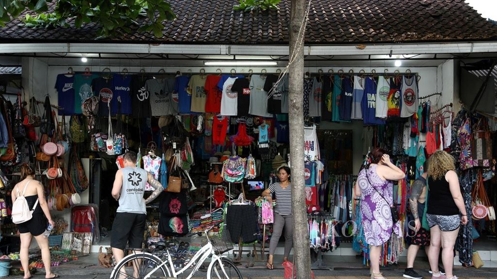 Turis mancanegara melihat berbagai produk kerajinan dan pakaian yang ditawarkan di toko-toko di kawasan Sanur, Bali, Minggu (9/9/2018). 