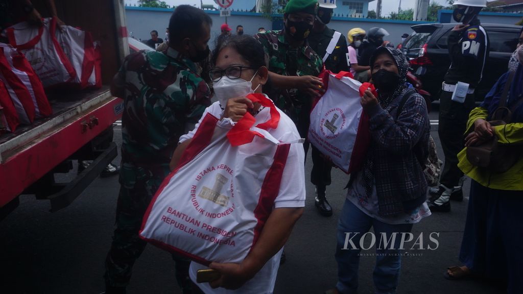Warga menunjukkan tas berisi bantuan dari Presiden Joko Widodo yang dibagikan di Pasar Serangan, Yogyakarta, Jumat (1/5/2022). Total ada 1.200 paket bantuan yang dibagikan. Warga antusias menyambut pembagian bantuan berisi bahan pokok tersebut.