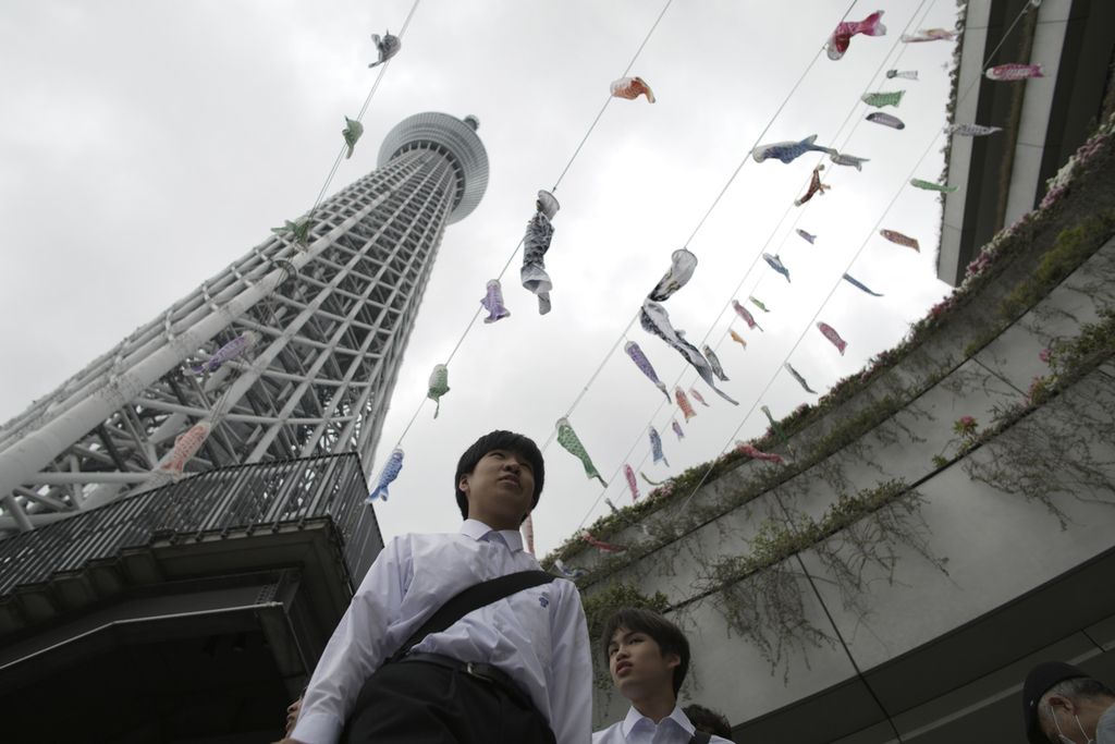 Pelajar Jepang di bawah layang-layang berbentuk ikan mas atau <i>koinobori</i>, yang dipasang di menara Tokyo Skytree di Tokyo, 30 April 2024. Gen Z Jepang menjadi sasaran rekrutmen jaringan kejahatan baru, Tokuryu. 