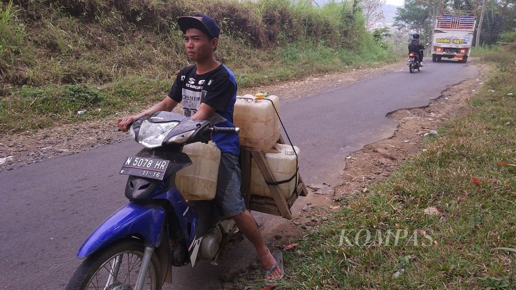 Mengendarai sepeda motor, seorang warga Dusun Kerisik, Desa Kemiri, Kecamatan Jabung, Kabupaten Malang, Jawa Timur, beberapa waktu lalu, mengangkat sejumlah jeriken air bersih dari mata air yang debitnya berkurang akibat kemarau.