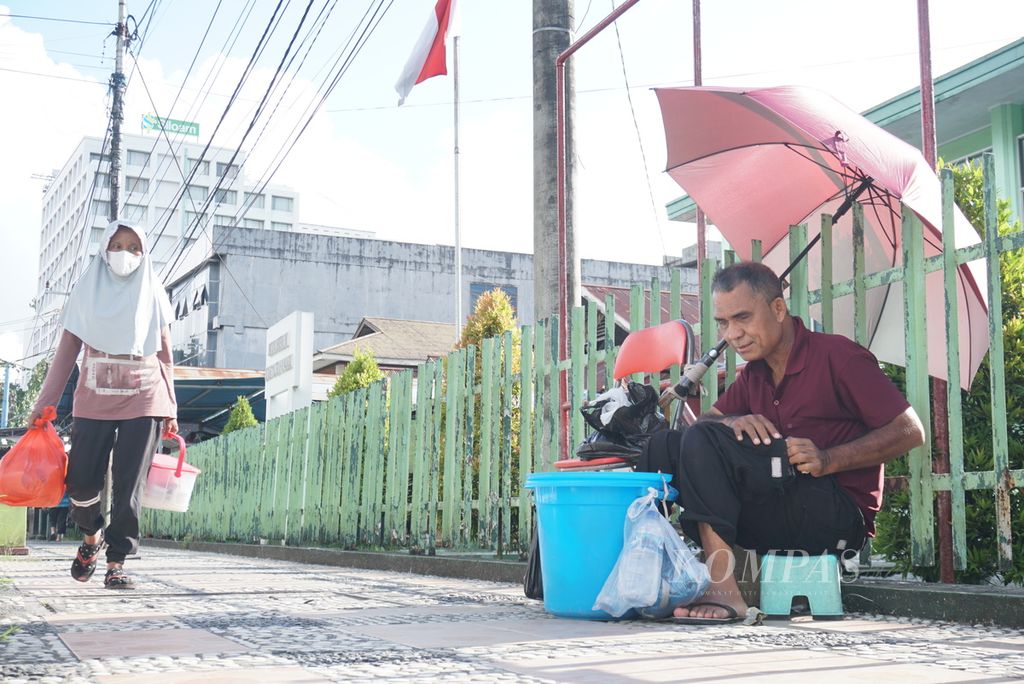 Gurinces Muli (60), seorang difabel netra, berjualan makanan ringan di trotoar Jalan Sam Ratulangi, Manado, Sulawesi Utara, Sabtu (16/4/2022).