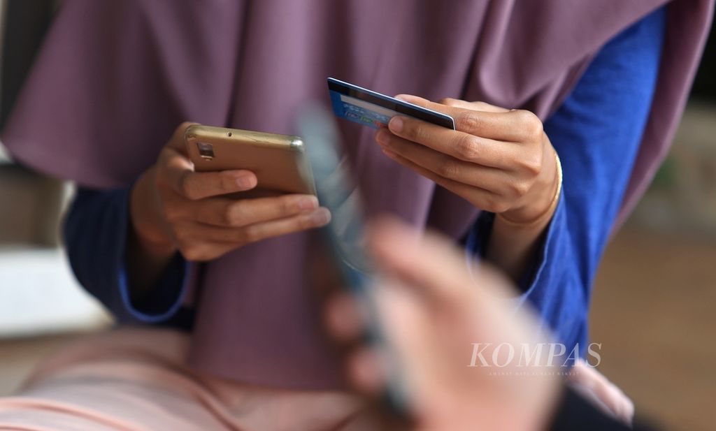 Transaksi elektronik melalui ponsel kini menjadi hal umum ditemui seperti yang dilakukan Rika Apriani di Serua, Depok, Jawa Barat, Minggu (11/9/2022).  