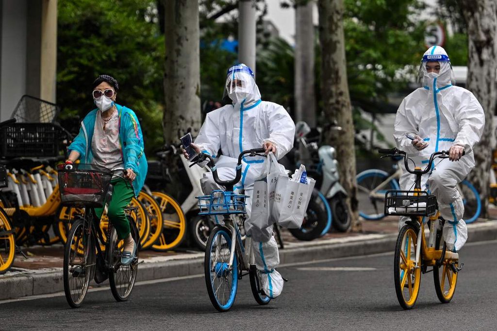 Pekerja dengan baju pelindung diri naik sepeda di jalan ketika berlangsung penguncian wilayah total di Distrik Jingan, Shanghai, China, 29 Mei 2022. 