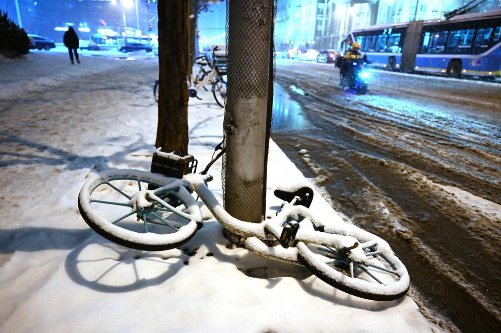 Sebuah sepeda yang tertutup salju tergeletak di trotoar saat hujan salju di Beijing, China, Kamis (14/12/2023).