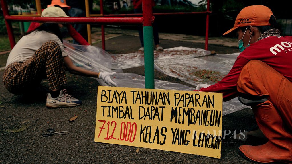 Pekerja mengumpulkan cat yang sudah dikelupas di Ruang Publik Terpadu Ramah Anak (RPTRA) Amir Hamzah, Pegangsaan, Menteng, Jakarta Pusat, 28 Oktober 2021.
