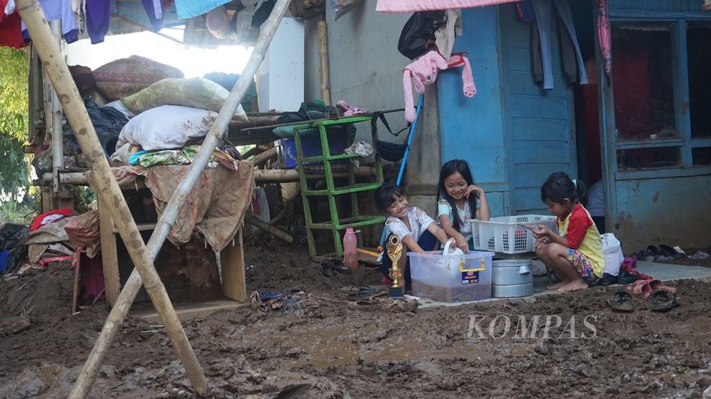 Sejumlah anak yang tinggal lebih kurang 40 meter dari bantaran Sungai Cisangkuy di Desa Kamasan, Kecamatan Banjaran, Kabupaten Bandung, membersihkan barang-barang yang terendam lumpur banjir, Minggu (8/12/2019). Daerah tersebut dilanda banjir bandang pada Jumat (6/12), dari pukul 19.00 hingga lewat tengah malam.