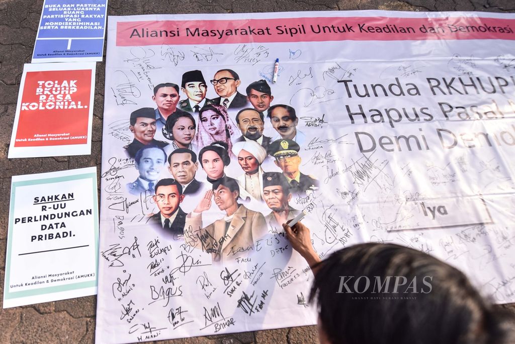Warga menandatangani spanduk Aliansi Masyarakat untuk Keadilan Demokrasi yang menolak Rancangan Kitab Undang-undang Hukum Pidana (RUU KUHP) di Bundaran Hotel Indonesia, Jakarta, Minggu (15/9/2019). 