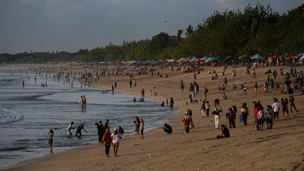 A number of tourists enjoy the atmosphere of Kuta Beach, Bali, ahead of sunset, Monday (11/10/2021).