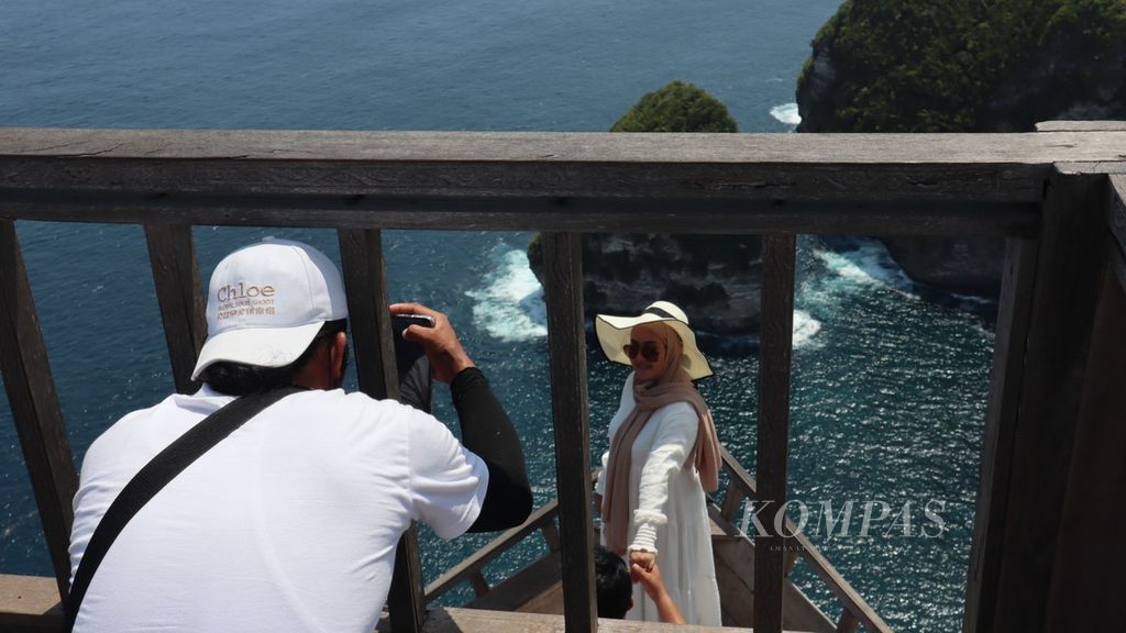 Para pemandu wisata tengah memfoto turis yang dibawanya dengan kamera ponsel, di Pulau Nusa Penida, Kabupaten Klungkung, Bali, Rabu (23/3/2022).