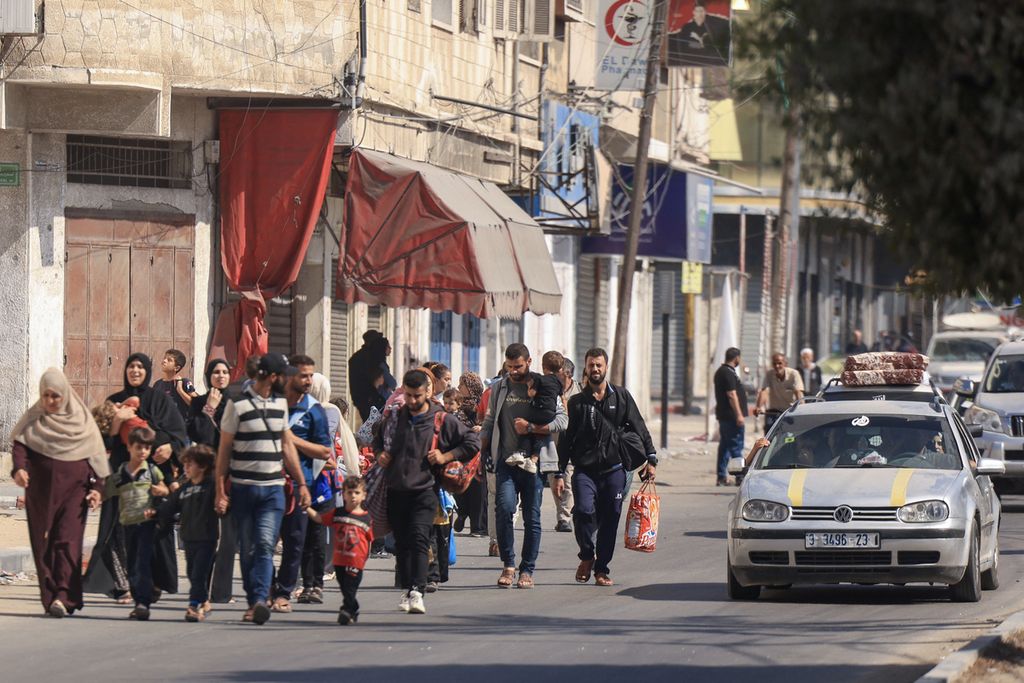 Warga Palestina membawa harta benda yang tersisa untuk mengungsi ke daerah yang lebih aman di Kota Gaza setelah serangan udara Israel, pada 13 Oktober 2023. Israel menyerukan relokasi segera bagi 1,1 juta orang di Gaza. 