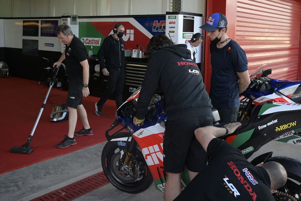 Pebalap LCR Honda, Alex Marquez (kanan), menyaksikan mekaniknya memasukkan sepeda motornya ke garasi tim MotoGP itu di Sirkuit Termas de Rio Hondo, Kamis (31/3/2022) waktu setempat.