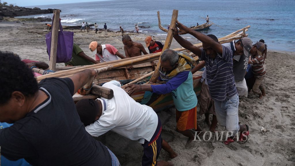 Nelayan bergotong royong mendorong perahu menuju rumah penyimpanan <i>peledang </i>atau perahu di Desa Lamalera A, Kecamatan Wulandoni, Kabupaten Lembata, Nusa Tenggara Timur, Jumat (11/8/2023).