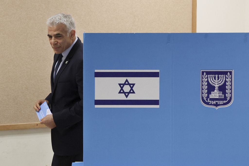 Penjabat Perdana Menteri Israel Yair Lapid keluar dari sebuah bilik suara di sebuah tempat pemungutan suara di Tel Aviv, Selasa (1/11/2022). Hasil jajak pendapat memperlihatkan Likud bersama sejumlah partai sayap kanan diprediksi memenangi pemilihan. Lapid meminta para pihak tidak mengklaim kemenangan sampai hasil penghitungan suara resmi keluar.