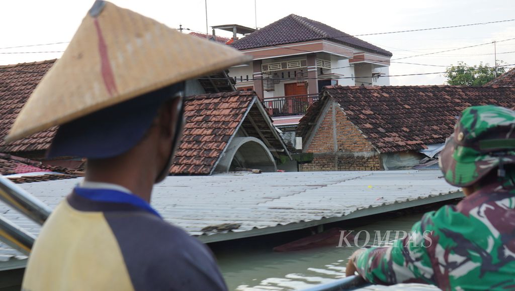Warga menggunakan perahu menyusuri perkampungan yang terdampak banjir, di Desa Ketanjung, Kecamatan Karanganyar, Kabupaten Demak, Jawa Tengah, Senin (18/3/2024). Banjir itu dipicu jebolnya tanggul Sungai Wulan yang berbatasan langsung dengan perkampungan tersebut. 