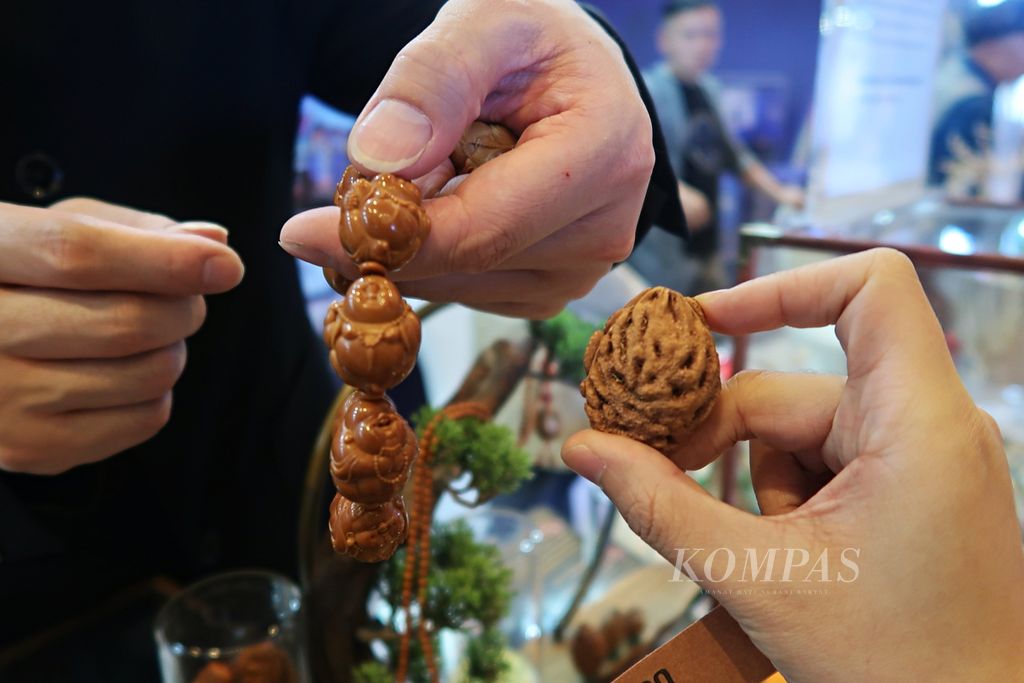 Seniman <i>hediao</i> asal Hunan, Ma Luo Cheng, menunjukkan perbandingan gelang berbentuk Buddha yang telah selesai dikerjakan dengan biji buah yang belum diukir dalam acara jamuan makan malam World Tourism Cities Federation (WTCF) Changsha Fragrant Hills Tourism Summit 2023 di Changsha, Hunan, Selasa (9/5/2023).