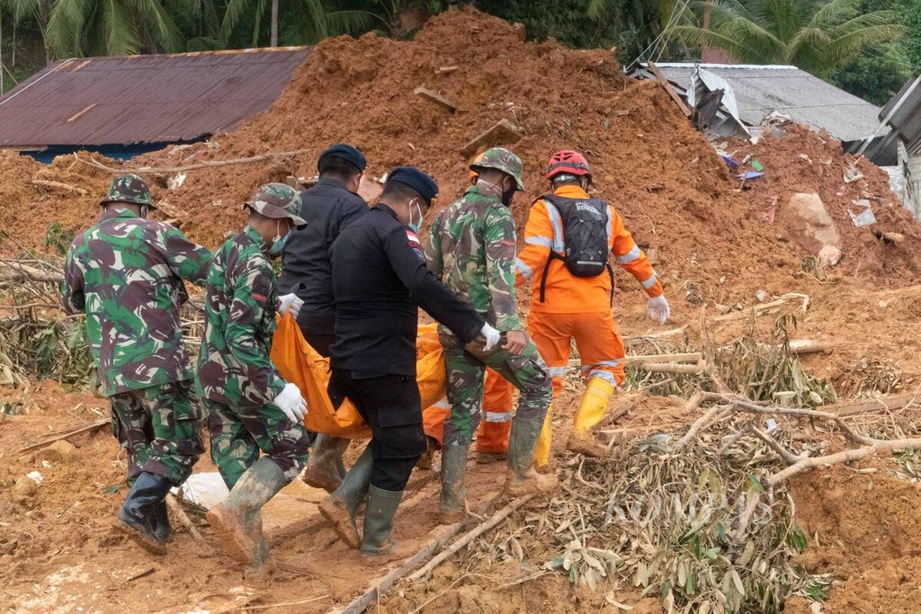 Tim SAR gabungan melintasi timbunan material longsor dan runtuhan bangunan saat mengevakuasi korban tewas di Kampung Genting, Desa Pangkalan, Kecamatan Serasan, Kabupaten Natuna, Kepulauan Riau, Kamis (9/3/2023). 