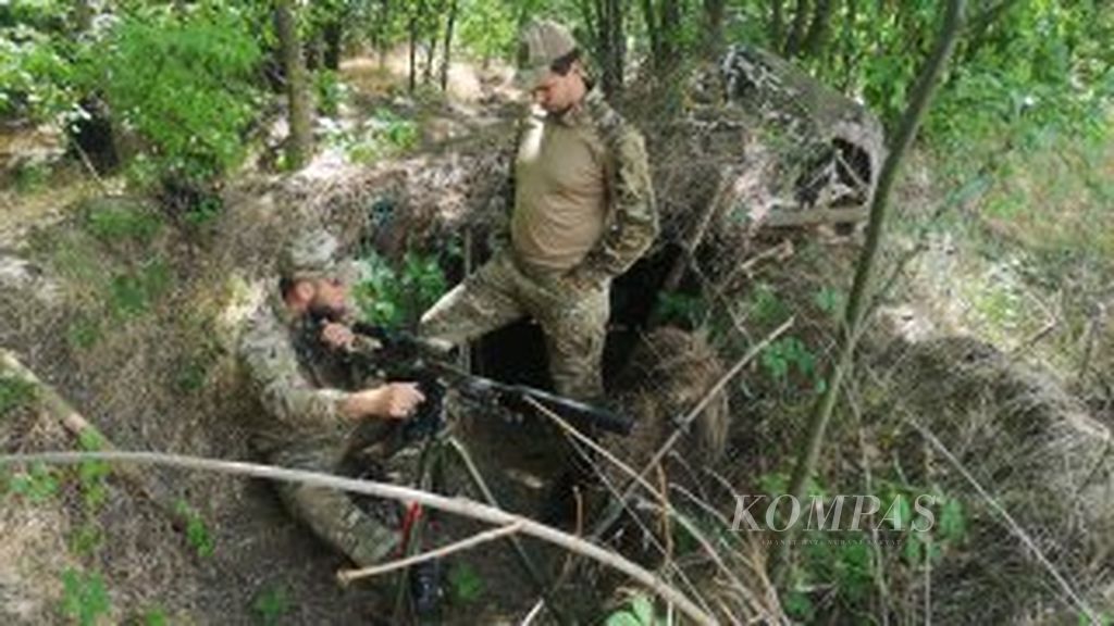 Dua milisi berbincang di sebuah parit pertahanan di daerah Ukraina bagian selatan, Kamis (23/6/2022). Parit ini digunakan sebagai wilayah pertahanan milisi Ukraina saat ada serangan Rusia.