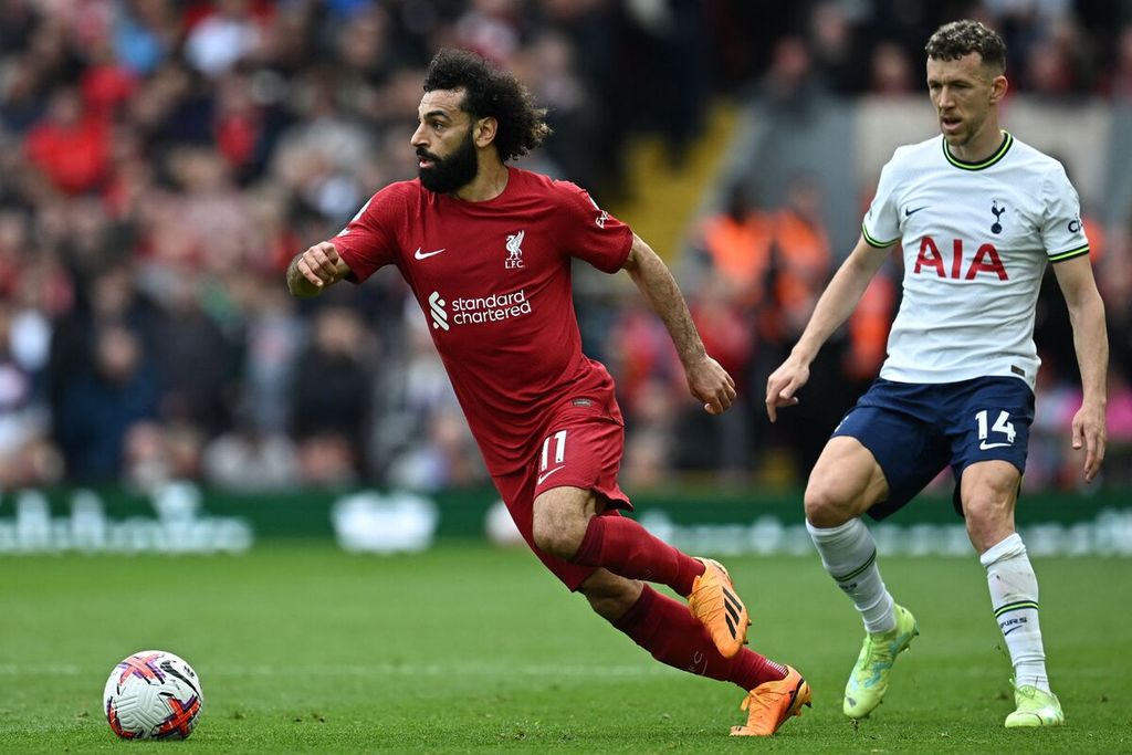 Pemain Liverpool, Mohamed Salah (kiri) lari menghindari adangan pemain Tottenham Hotspur, Ivan Perisic, pada laga Liga Inggris di Stadion Anfield, Liverpool, Minggu (30/4/2023) dini hari. Liverpool memenangi laga dengan skor 4-3.