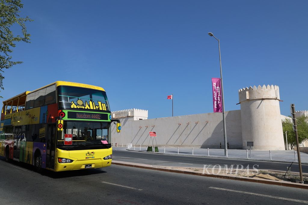 Bus melewati bendera Piala Dunia 2022 yang terpasa di depan Benteng Al Koot, salah satu tempat bersejarah di kawasan Msheireb, kota Doha, Qatar (17/11/2022). Moblitas warga dan suporter dari berbagai negara meningkatkan konsumsi BBM transportasi publik.